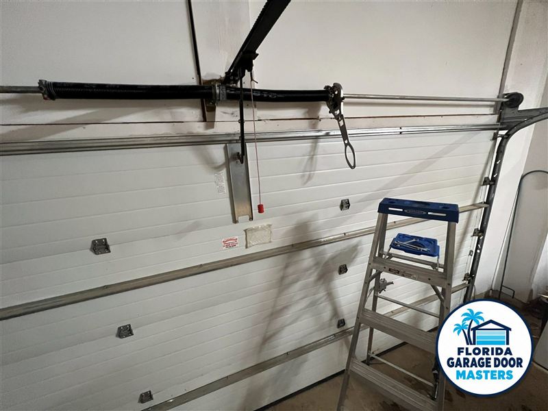 Garage door with a snapped lift cable hanging from the torsion bar