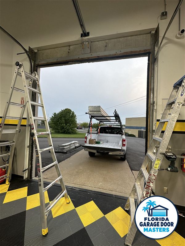 Commercial overhead door open during service with ladders in place