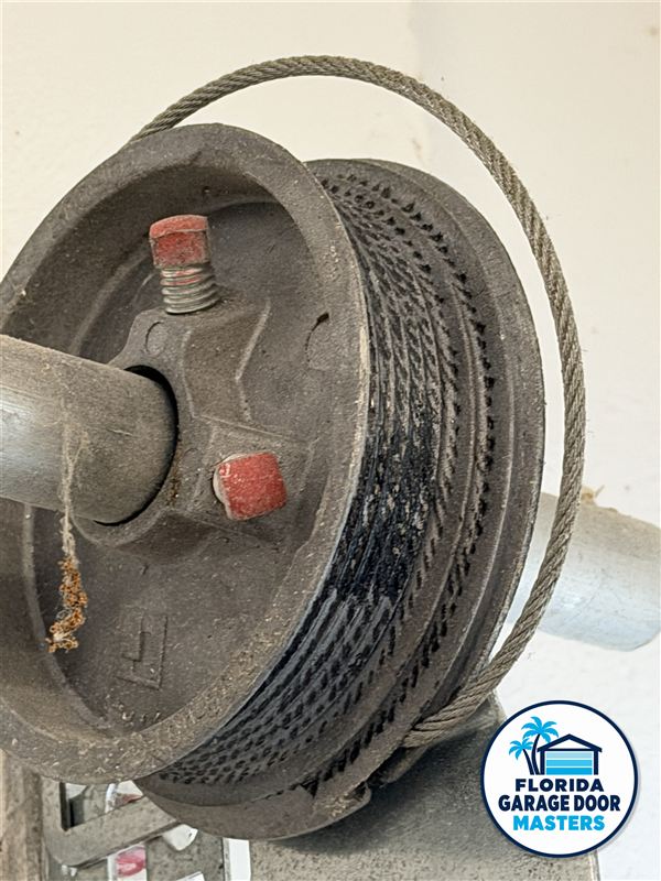 Frayed garage door lift cable wound on the cable drum