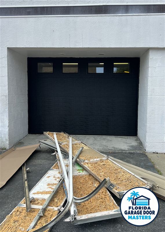 Modern black garage door installed, with the old door removed in front